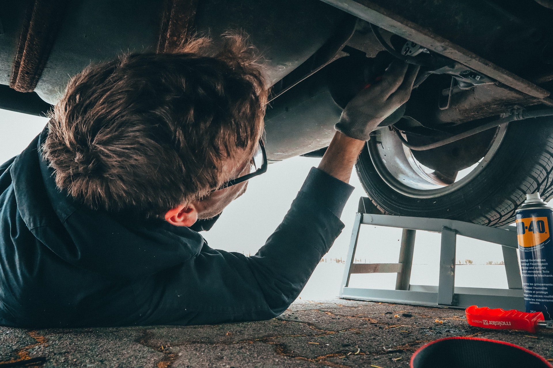 Mechanic working on bottom of vehicle at Long Island City Service Department 