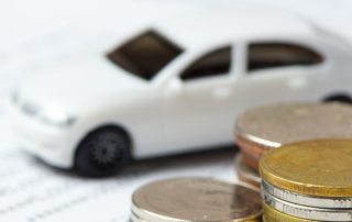 Miniature car with stack of coins on top of paperwork - Car Loan With Bad Credit concept image