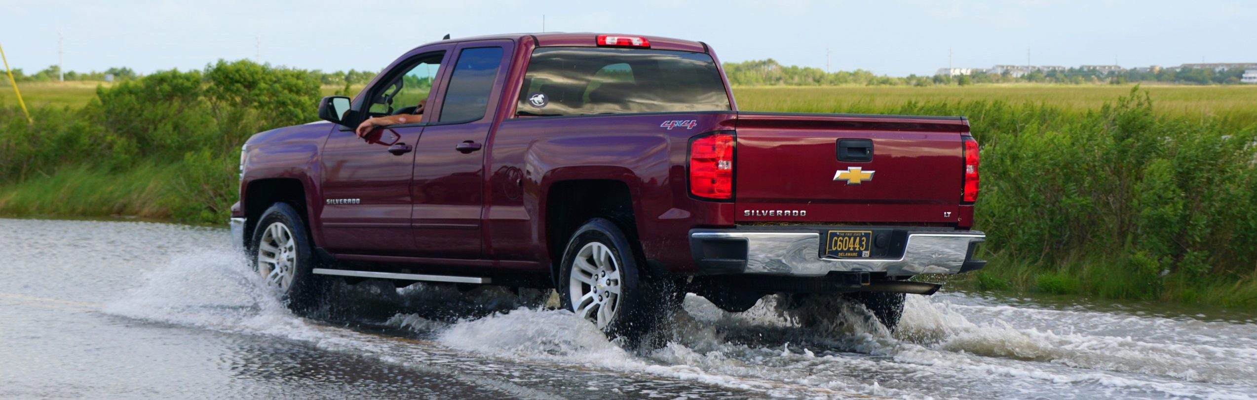 A red Chevy Silverado truck passing the flooded road - Are Chevys good cars and are chevy trucks reliable concept image